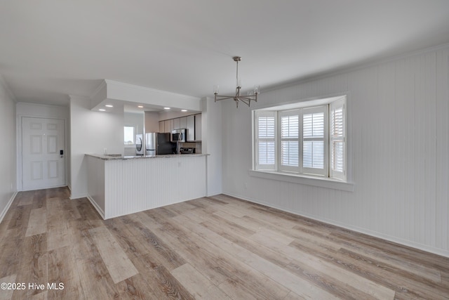 kitchen with plenty of natural light, appliances with stainless steel finishes, light wood-type flooring, and a chandelier