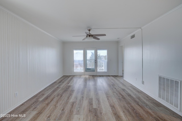 empty room with ornamental molding, wood finished floors, visible vents, and a ceiling fan