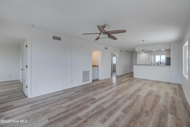 unfurnished living room with light wood-style floors, visible vents, a sink, and ceiling fan with notable chandelier