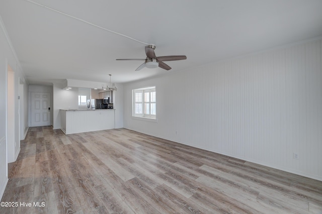 unfurnished living room with light wood-style floors and ceiling fan with notable chandelier