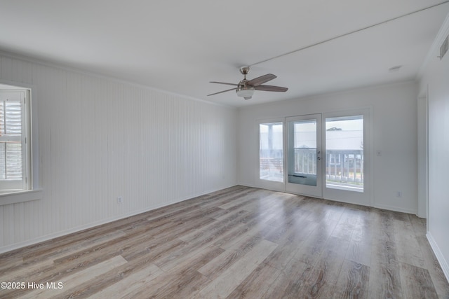 spare room featuring crown molding, ceiling fan, baseboards, and light wood-style floors