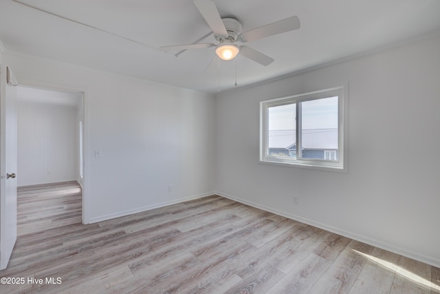 spare room featuring a ceiling fan, crown molding, light wood-style flooring, and baseboards