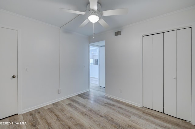 unfurnished bedroom featuring wood finished floors, visible vents, baseboards, a closet, and crown molding