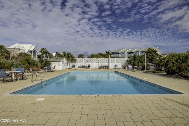 pool featuring an outbuilding, a patio area, fence, and a shed