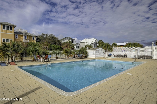 view of swimming pool with a fenced in pool, an outbuilding, a patio, fence, and a shed