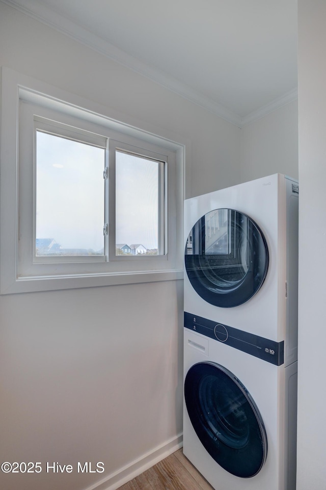 washroom with laundry area, stacked washer / dryer, wood finished floors, baseboards, and ornamental molding