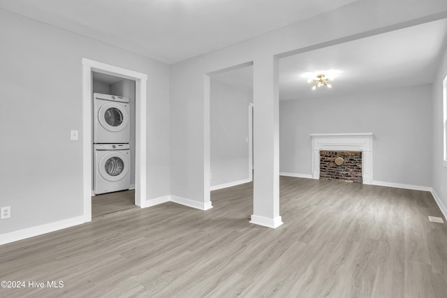 interior space featuring a fireplace, light hardwood / wood-style flooring, and stacked washing maching and dryer