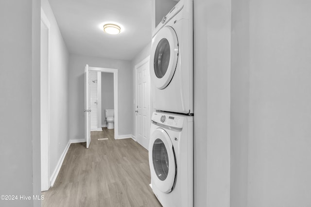 clothes washing area featuring light hardwood / wood-style floors and stacked washer / dryer