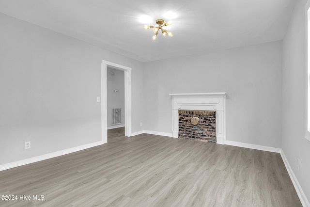 unfurnished living room featuring light wood-type flooring and a brick fireplace