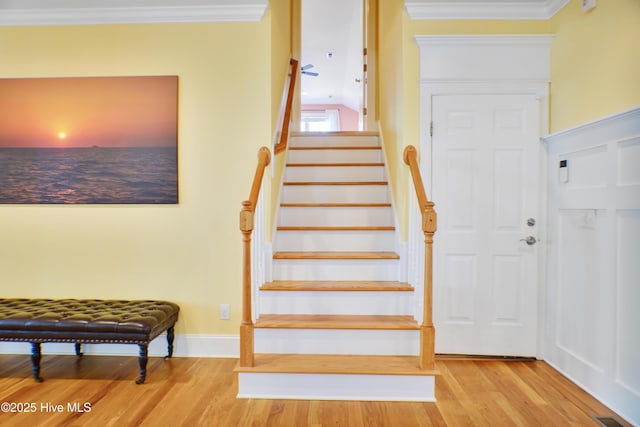 stairs featuring hardwood / wood-style floors and ornamental molding