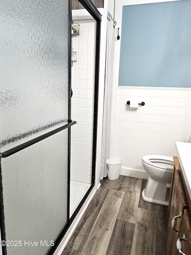 bathroom with vanity, toilet, a shower with door, and wood-type flooring