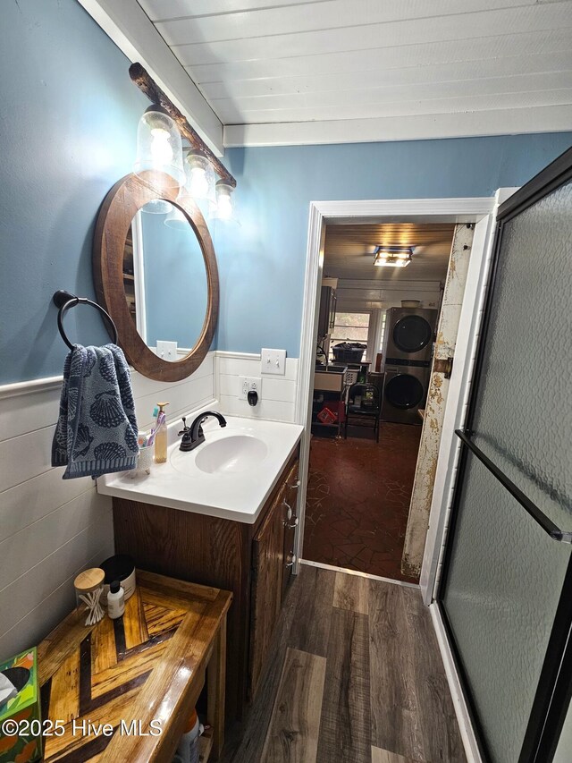 bathroom featuring wood-type flooring, tile walls, vanity, and washer / dryer