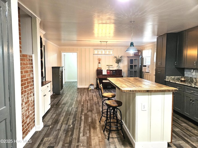 kitchen featuring brick wall, pendant lighting, a center island, butcher block counters, and gray cabinetry