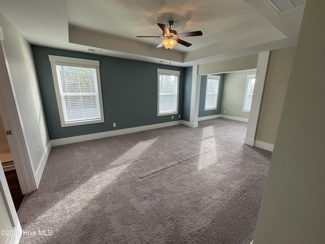 empty room featuring light carpet, ceiling fan, and a tray ceiling