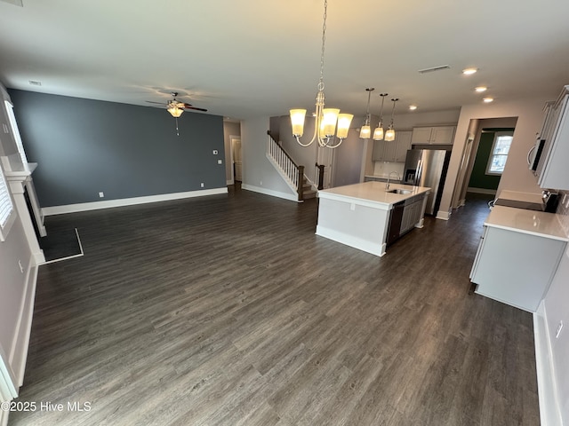 kitchen featuring sink, hanging light fixtures, a center island with sink, stainless steel fridge, and dark hardwood / wood-style floors