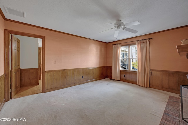 unfurnished room featuring ceiling fan, light colored carpet, a textured ceiling, and crown molding