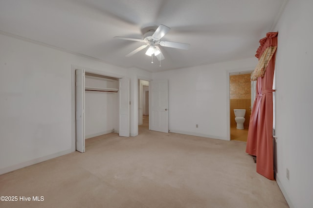 unfurnished bedroom featuring light colored carpet, a closet, ceiling fan, and ensuite bathroom