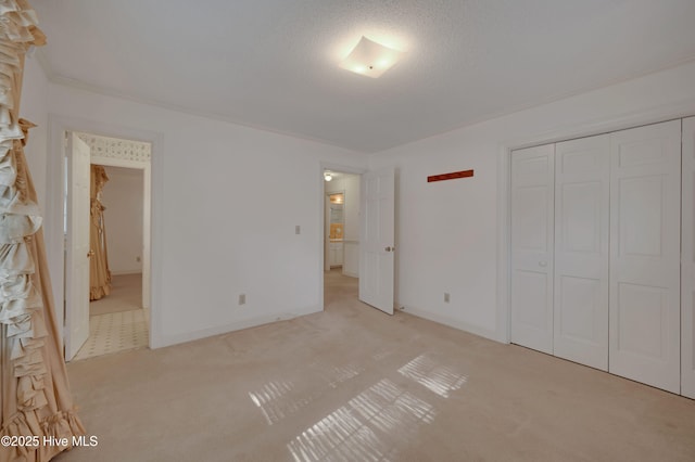 unfurnished bedroom featuring a textured ceiling, a closet, and light carpet