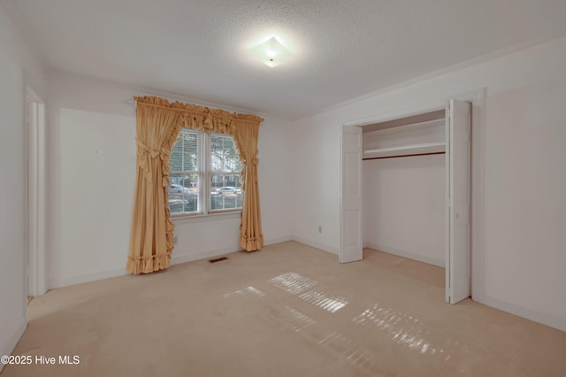 unfurnished bedroom with a textured ceiling, carpet flooring, and a closet