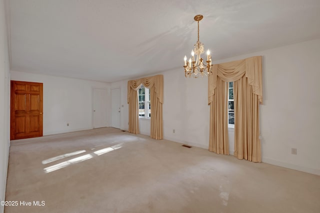 unfurnished room featuring a notable chandelier and light colored carpet