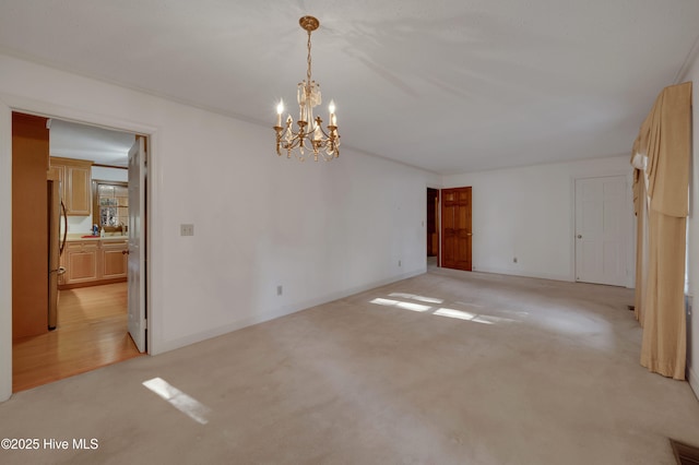 carpeted spare room with an inviting chandelier