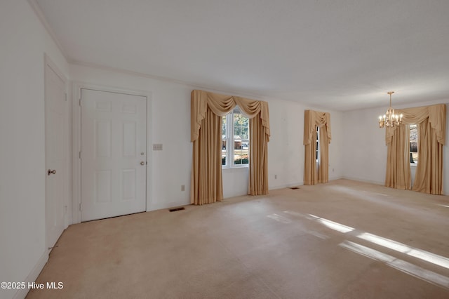 carpeted spare room with ornamental molding and an inviting chandelier