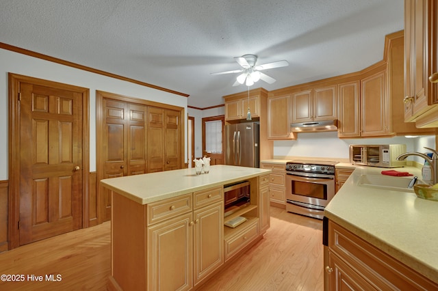 kitchen featuring appliances with stainless steel finishes, a textured ceiling, sink, a kitchen island, and light hardwood / wood-style flooring