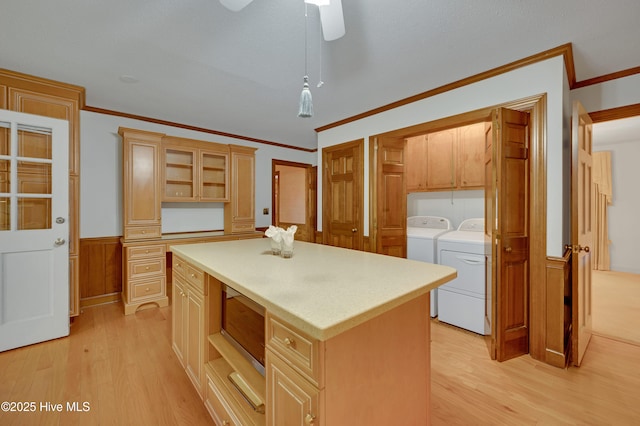 kitchen featuring washing machine and dryer, a kitchen island, decorative light fixtures, light hardwood / wood-style floors, and ornamental molding