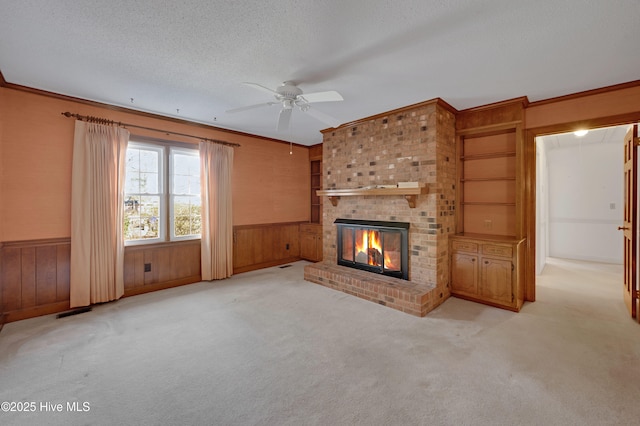 unfurnished living room featuring a textured ceiling, crown molding, light carpet, and a fireplace