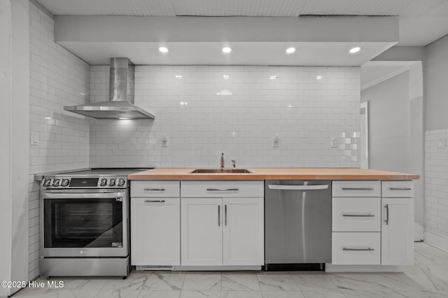 kitchen featuring wood counters, white cabinets, wall chimney exhaust hood, and appliances with stainless steel finishes