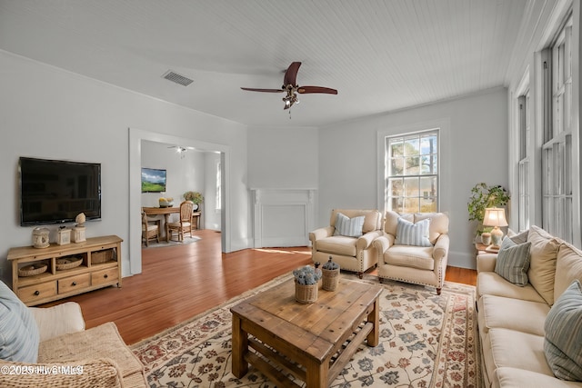 living room with crown molding, light hardwood / wood-style flooring, and ceiling fan