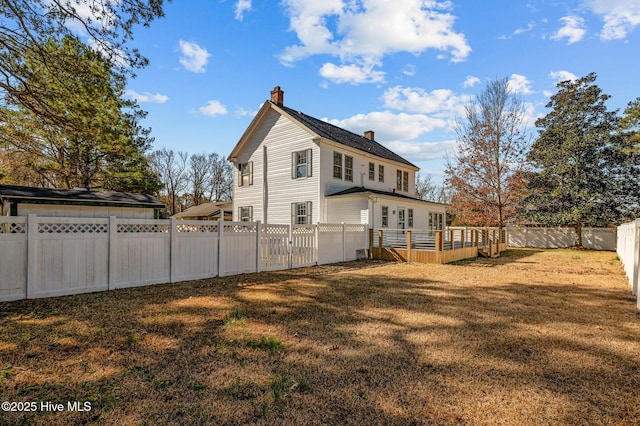 back of property featuring a wooden deck and a yard