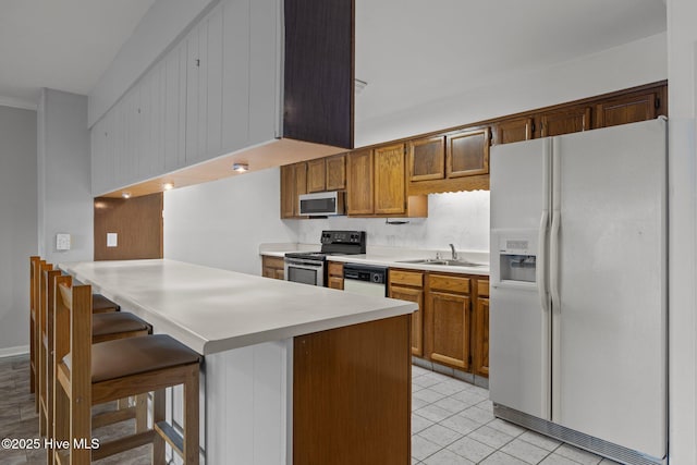 kitchen with sink, light tile patterned floors, stainless steel appliances, a kitchen bar, and kitchen peninsula