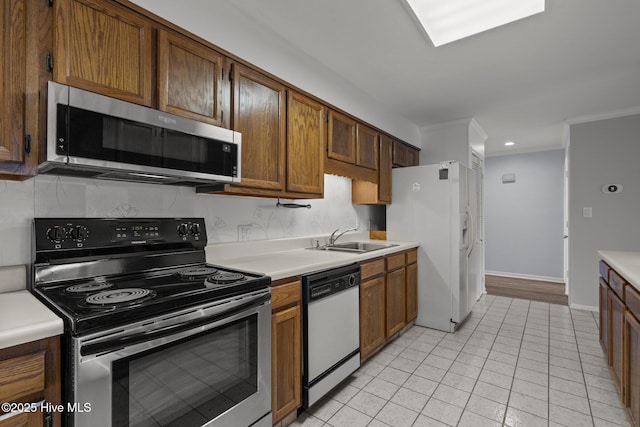 kitchen with appliances with stainless steel finishes, sink, backsplash, ornamental molding, and light tile patterned floors