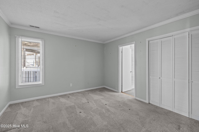 unfurnished bedroom with crown molding, light carpet, a textured ceiling, and a closet