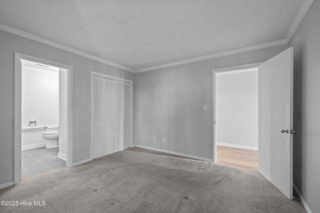 unfurnished bedroom with crown molding, ensuite bath, a closet, and light carpet