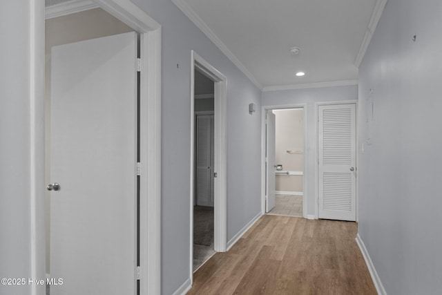 hall with ornamental molding and light hardwood / wood-style floors