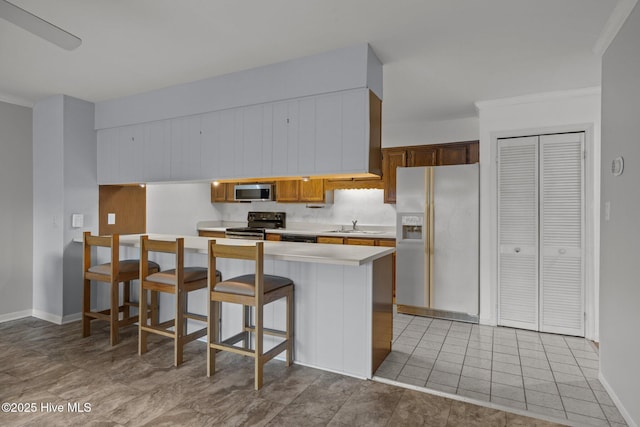 kitchen featuring sink, range with electric cooktop, a kitchen breakfast bar, white refrigerator with ice dispenser, and kitchen peninsula