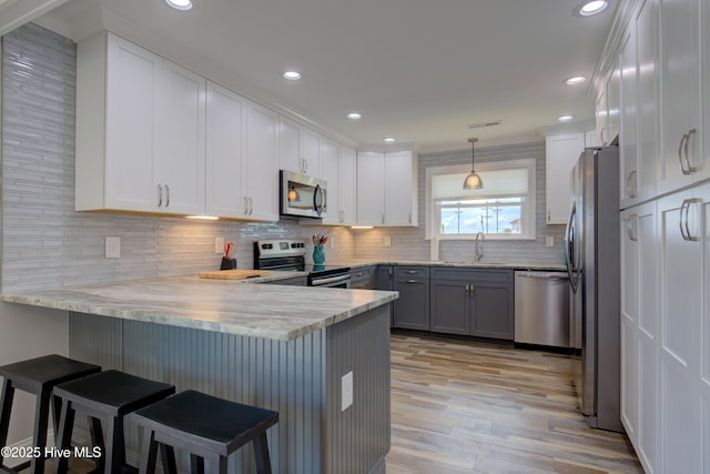 kitchen with a kitchen breakfast bar, sink, kitchen peninsula, and appliances with stainless steel finishes