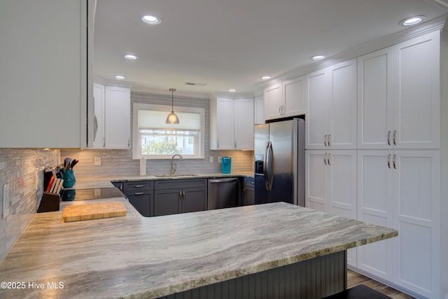 kitchen featuring kitchen peninsula, pendant lighting, appliances with stainless steel finishes, sink, and white cabinetry