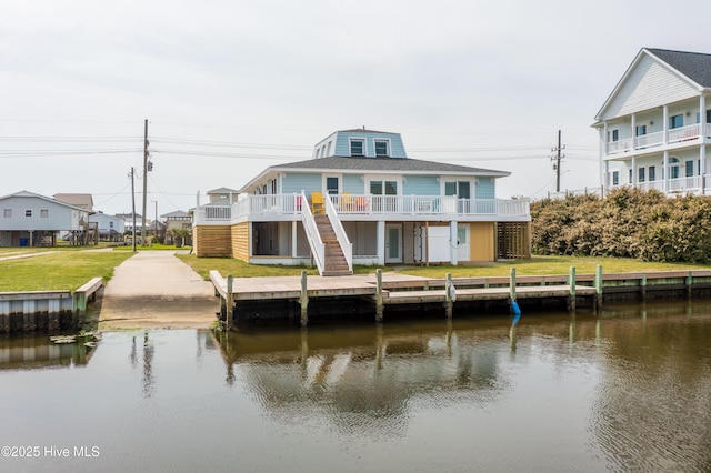 rear view of property featuring a deck with water view and a lawn