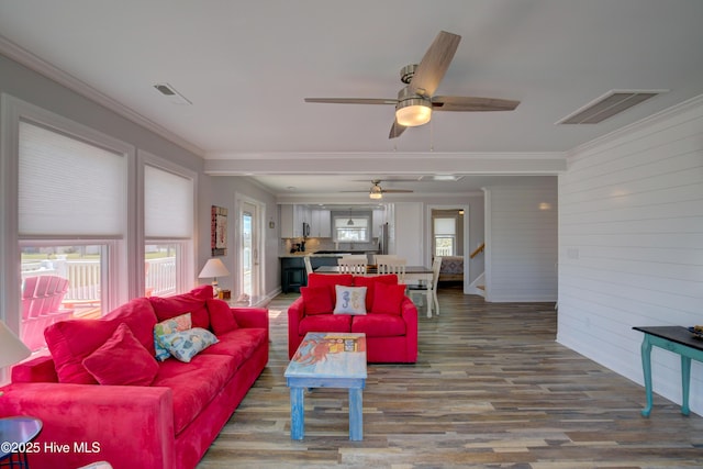 living room with ornamental molding, wooden walls, and hardwood / wood-style floors