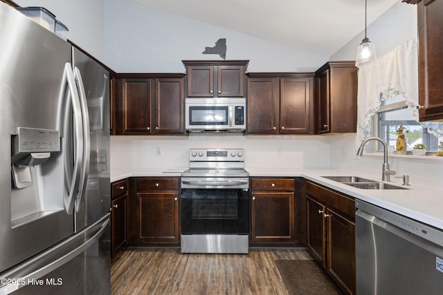 kitchen with pendant lighting, sink, lofted ceiling, dark wood-type flooring, and stainless steel appliances