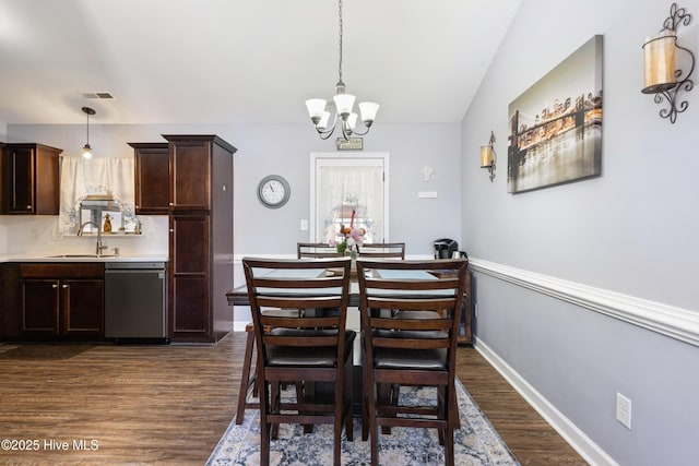 dining space featuring lofted ceiling, sink, an inviting chandelier, and dark hardwood / wood-style floors