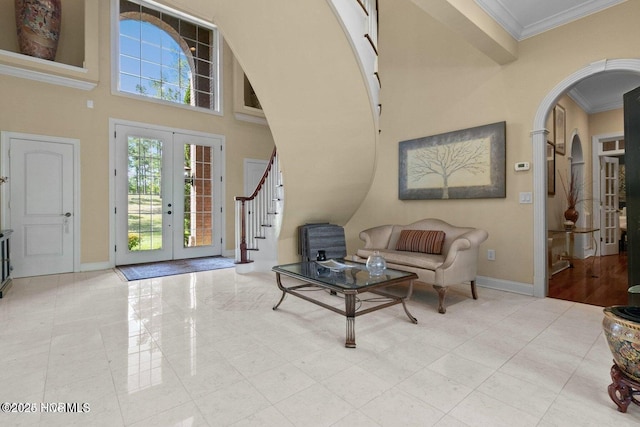 entrance foyer with baseboards, arched walkways, stairway, crown molding, and french doors