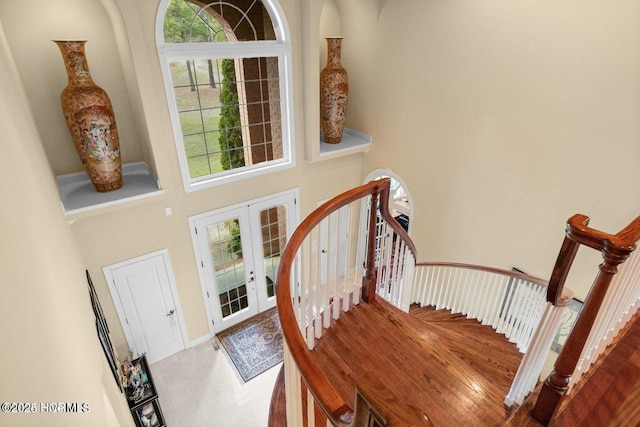 foyer entrance with a towering ceiling, stairway, and french doors