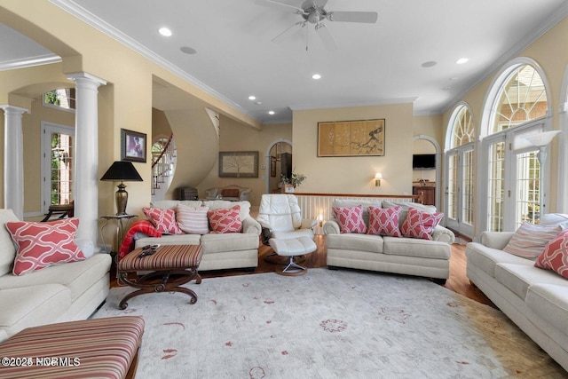 living room featuring ornate columns, arched walkways, wood finished floors, and ornamental molding