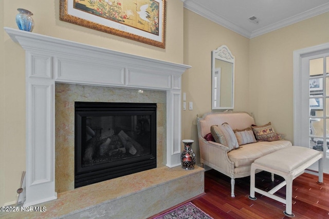 sitting room with crown molding, visible vents, dark wood-type flooring, and a high end fireplace