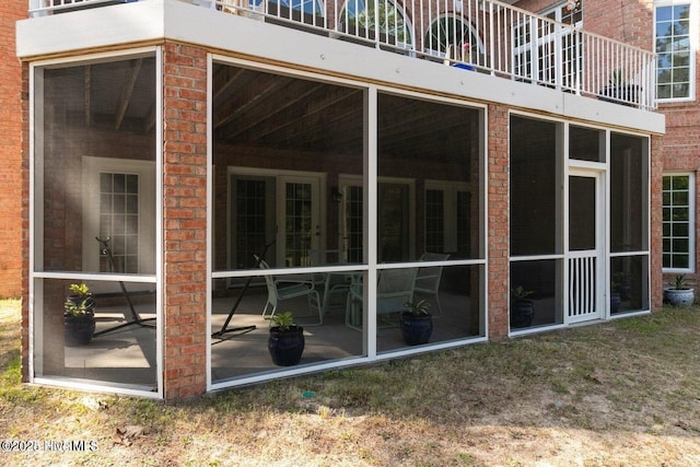 view of property exterior featuring a sunroom and brick siding