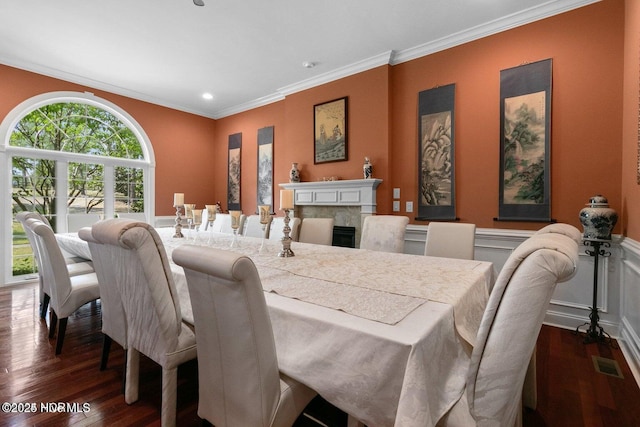 dining area featuring dark wood-style floors, visible vents, a premium fireplace, ornamental molding, and wainscoting